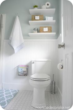 a white toilet sitting in a bathroom next to a shelf filled with towels and other items