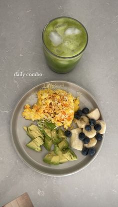 a white plate topped with food next to a green smoothie and cup filled with liquid