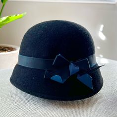 Black Cloche Hat 100% Wool. Its Classic Silhouette Is Accented With A Grosgrain Blue And Black Ribbon Cloche Is French For "Bell." A Cloche Hat Is A Type Of Women's Hat That Features A Distinctive Bell Shape And A Close-Fitting, Short-Brimmed Style - Hence The Name. These Happening Hats Have Been Around For More Than A Century And First Became Popular All The Way Back In The 1920s And '30s, When They Were Primarily Made Of Felt. They Were Also Made Of Beads Or Lace For Evening Wear And In Later Adjustable Brimmed Black Cloche Hat, Adjustable Black Brimmed Cloche Hat, Classic Black Mini Hat For Winter, Classic Black Wool Cloche Hat, Black Wool Hat With Short Brim, Fitted Black Cloche Hat Casual Style, Black Fitted Cloche Hat Casual, Black Fitted Cloche Hat Casual Style, Black Casual Cloche Hat