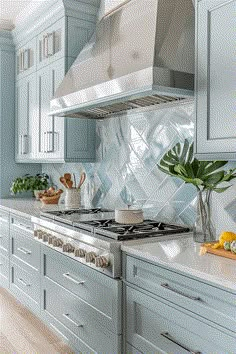 a kitchen with blue cabinets and stainless steel stove top oven, white marble counter tops and wooden flooring