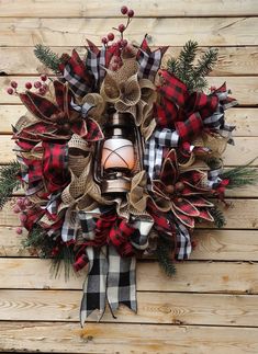 a christmas wreath with a lantern hanging from it's side on a wooden wall