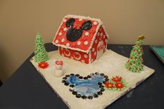 a cake shaped like a house with mickey mouse decorations on the front and side, sitting on top of a table