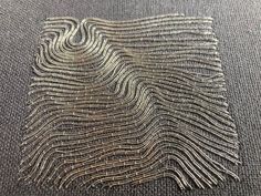 a piece of silver thread on top of a gray carpet with an image of wavy lines in the middle