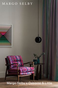 a living room with a colorful chair next to a painting on the wall and a table