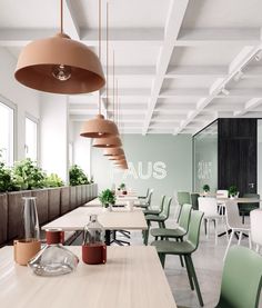 an empty dining room with green chairs and plants hanging from the ceiling in front of it