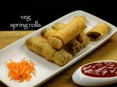 vegetable spring rolls on a plate with carrots and ketchup next to it