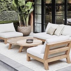 an outdoor living area with white furniture and potted plants