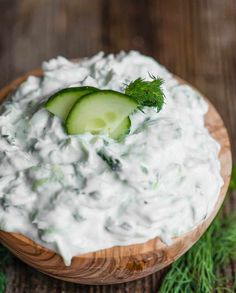 a wooden bowl filled with cucumber and sour cream