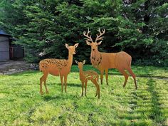 three wooden deer standing on top of a lush green field