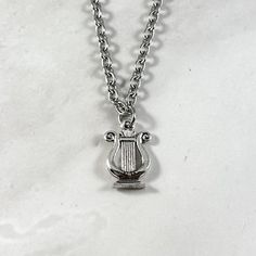 a silver necklace with a small harp on it's back end hanging from a chain