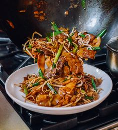 a white plate topped with meat and veggies on top of a stove