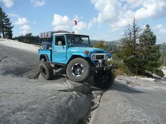 a blue jeep driving down a rocky road