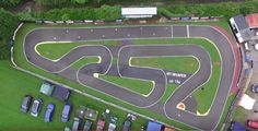 an aerial view of a race track with cars parked on the side and green grass around it