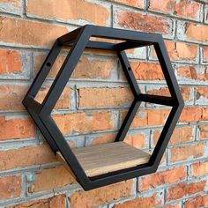 a black hexagonal shelf mounted to the side of a brick wall