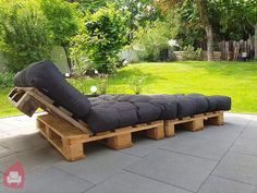 an outdoor lounge chair made out of wooden pallets and black cushions is sitting on the patio