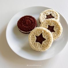 three crocheted cookies on a white plate