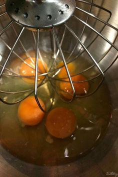 three eggs are being cooked in a metal bowl with a strainer on the side