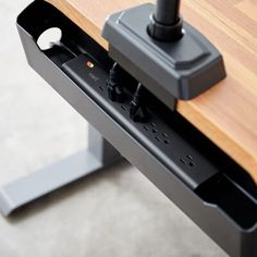 an electronic device is plugged into the side of a wooden table with metal legs