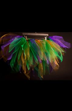 a multicolored skirt hanging from a metal hanger on a black background with clippings