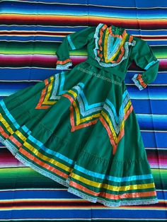 "Green Jalisco Mexican dress, Folkloric ribbon dress, Guadalajara folkore outfit, mexican festivities dance, folkloric dancer garnment, folk The Jalisco ribbon dress also called the Adelita dress, is the one used by folkloric dancers. The dress is widely used in Mexico and today represents an authentic Mexican style. Is perfect for mexican parties, cinco de mayo and folkloric dancers. Fits size 8 (8-9 years old) Measurements taken flat: Shoulder to shoulder 11 1/2\" Sleeve length 19 1/2\" Armpit Traditional Multicolor Fiesta Dress, Traditional Multicolor Dress For Fiesta, Multicolor Fiesta Dresses For Festivals, Multicolor Dresses For Fiesta Festivals, Multicolor Dresses For Fiesta And Festivals, Traditional Dress For Fiesta And Cinco De Mayo, Traditional Dress For Fiesta And Festivals, Traditional Ruffle Dress For Fiesta, Folklore Outfit