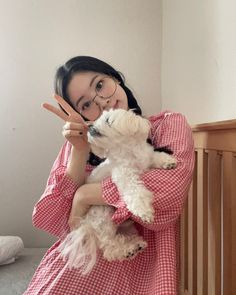 a woman holding a dog in her arms and making the peace sign with her fingers