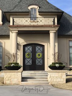 the front entrance to a large home with two wreaths on it's windows