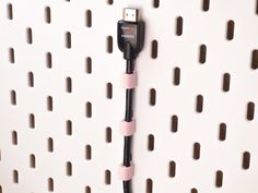 a black and pink charger plugged into a white wall with holes on it