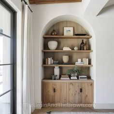 a wooden shelf with books and vases on it in front of a doorway that leads to another room