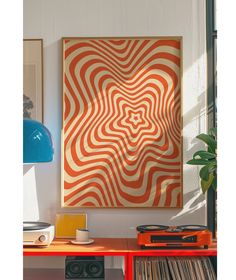 an orange and white abstract painting hangs on the wall above a red table with record players