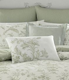 a bed with green and white comforters and pillows on top of it's headboard