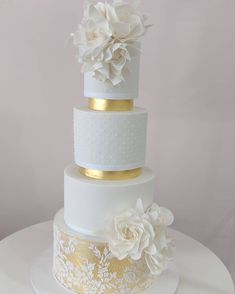 a white and gold wedding cake with flowers on top