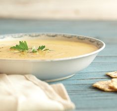 a white bowl filled with soup next to crackers