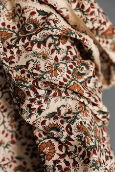 close up view of the fabric on a dress with red and green floral pattern,