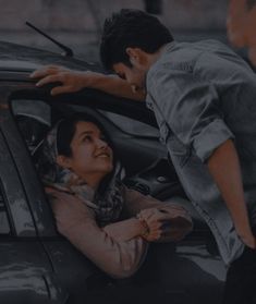 two people leaning out the window of a car