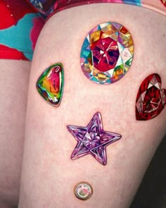 a woman's thigh with different colored jewels and stars on the side, as well as an ornament