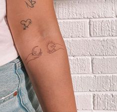 a woman's arm with tattoos on it and a brick wall in the background