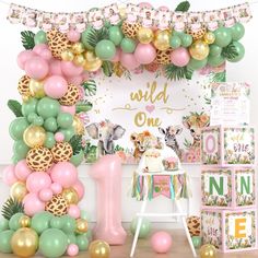 a pink, green and gold wild one birthday party set up with jungle animals balloons