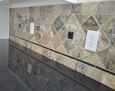 a tiled wall in a kitchen next to a stove top oven and counter with two light switches on each side