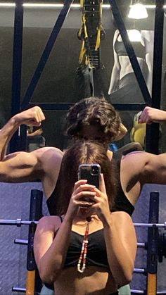 a woman taking a selfie in front of a mirror with her cell phone while working out