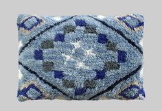 a blue pillow with an intricate design on the front and back, sitting on a gray surface