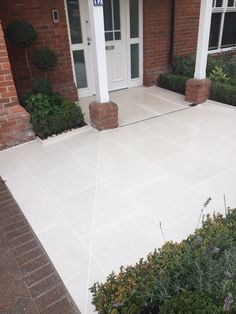 the front entrance to a brick house with white doors and plants growing on the sidewalk