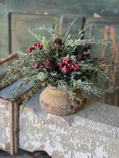 a vase filled with red flowers sitting on top of a wooden table next to a wall