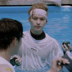 a man standing next to another person in a swimming pool