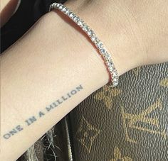 a close up of a person's arm with a bracelet on it and the words one in a million written on her wrist