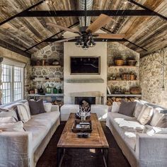 a living room with couches, tables and a fireplace in the middle of it