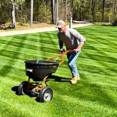 a man is pulling a wheelbarrow in the grass with his lawn mower