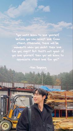 a man standing in front of a pile of wood next to a truck with a quote on it