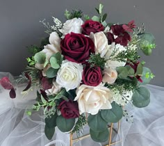 a bouquet of flowers sitting on top of a white cloth covered table next to a gray wall