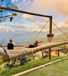 two people sitting on a hammock in the mountains