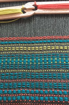 a close up view of some knitting needles and yarn on a tablecloth with different colors